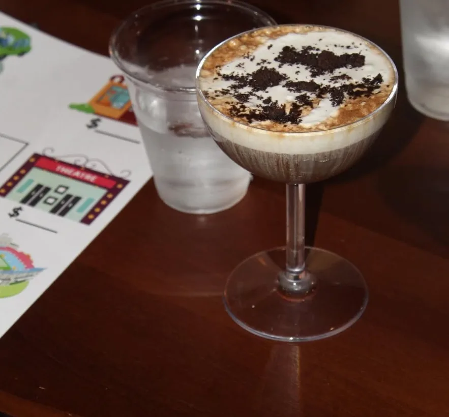 An espresso martini topped with cookie crumble in a coupe glass